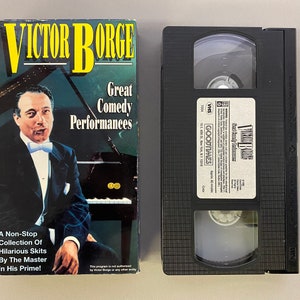 May include: VHS video cassette tape of Victor Borge's Great Comedy Performances. The cover features a black and white photo of Victor Borge sitting at a piano. The text on the cover reads "Victor Borge Great Comedy Performances A Non-Stop Collection Of Hilarious Skits By The Master In His Prime!"