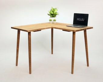 May include: A light wood corner desk with a laptop computer on the right side and a small potted plant on the left side. The desk has four legs and a simple design.