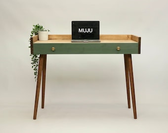May include: A green desk with a wooden top and a drawer. The desk has a laptop on top and a small plant hanging off the side. The desk has brass knobs on the drawer and wooden legs.