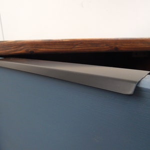 May include: A close-up of a dark wood cabinet with a blue painted drawer. The drawer has a black metal pull handle.