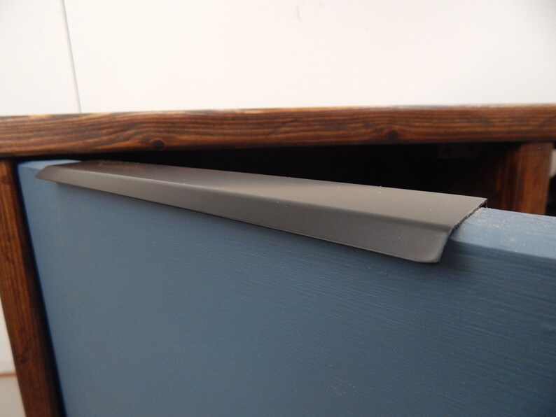 May include: A close-up of a dark wood cabinet with a blue painted drawer. The drawer has a black metal pull handle.