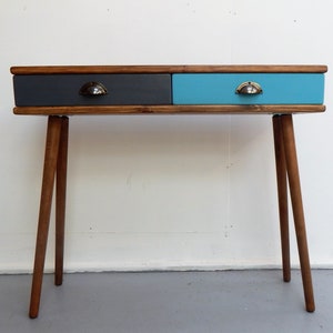 May include: A wooden console table with two drawers. The top drawer is grey and the bottom drawer is blue. The table has four wooden legs.