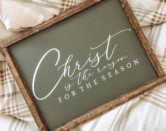 May include: A wooden framed sign with a dark green background and white lettering that reads "Christ is the reason for the season".