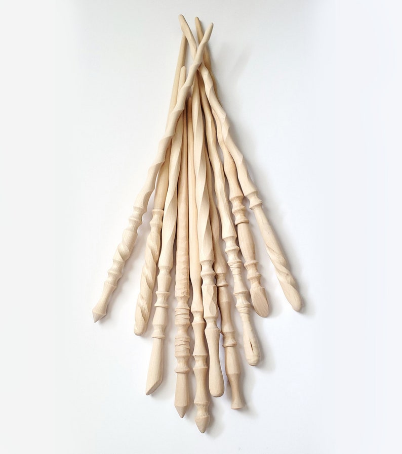 May include: A collection of 12 unfinished wooden wands, each with a unique shape and design. The wands are made of natural wood and have a smooth, polished finish.