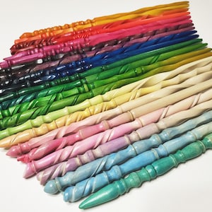 Pode incluir: Uma cole&ccedil;&atilde;o de varinhas de madeira coloridas em v&aacute;rias tonalidades, incluindo vermelho, laranja, rosa, verde, azul e tons de madeira natural. Cada varinha tem um design torcido e est&aacute; disposta em forma de leque, mostrando a gama de cores e estilos.