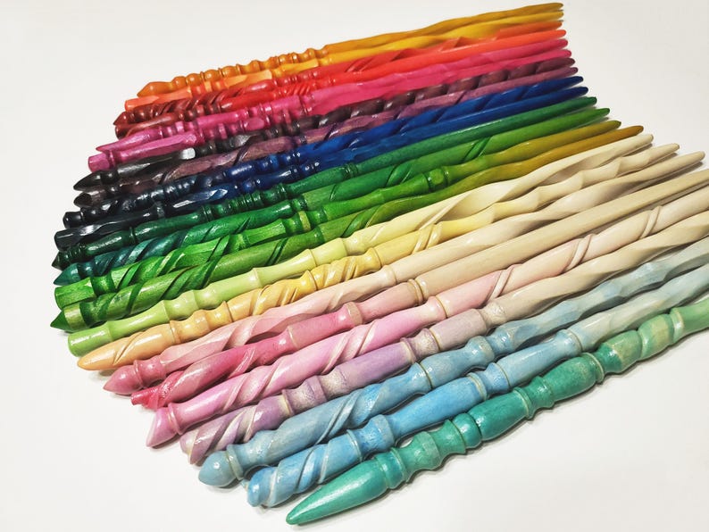 Pode incluir: Uma cole&ccedil;&atilde;o de varinhas de madeira coloridas em v&aacute;rias tonalidades, incluindo vermelho, laranja, rosa, verde, azul e tons de madeira natural. Cada varinha tem um design torcido e est&aacute; disposta em forma de leque, mostrando a gama de cores e estilos.