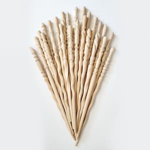 May include: A collection of 20 wooden wands, each with a unique design and shape. The wands are all natural wood color and are arranged in a fan shape.