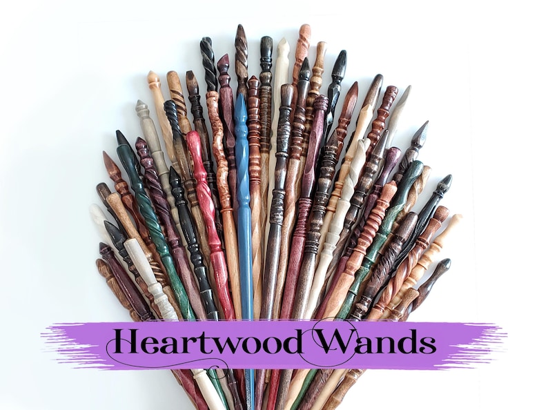 Pode incluir: Uma cole&ccedil;&atilde;o de varinhas de madeira artesanais em v&aacute;rias cores e designs, incluindo estilos torcidos, esculpidos e lisos. As varinhas est&atilde;o dispostas em forma de leque sobre um fundo branco, com o texto "Heartwood Wands" em uma faixa roxa.