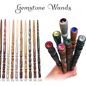 Puede incluir: Una colecci&oacute;n de Gemstone Wands que presenta diez varitas de madera etiquetadas de G11 a G20, cada una con una textura tallada &uacute;nica. Un segundo grupo muestra los mangos de las varitas rematados con varias piedras preciosas de colores, incluyendo rojo, amarillo, rosa, verde, azul y transparente.