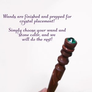 Puede incluir: Una varita de madera marr&oacute;n oscuro con un mango torneado y liso, rematada con un cristal esmeralda facetado y circular. El texto dice: Wands are finished and prepped for crystal placement! Simply choose your wand and stone color, and we will do the rest!