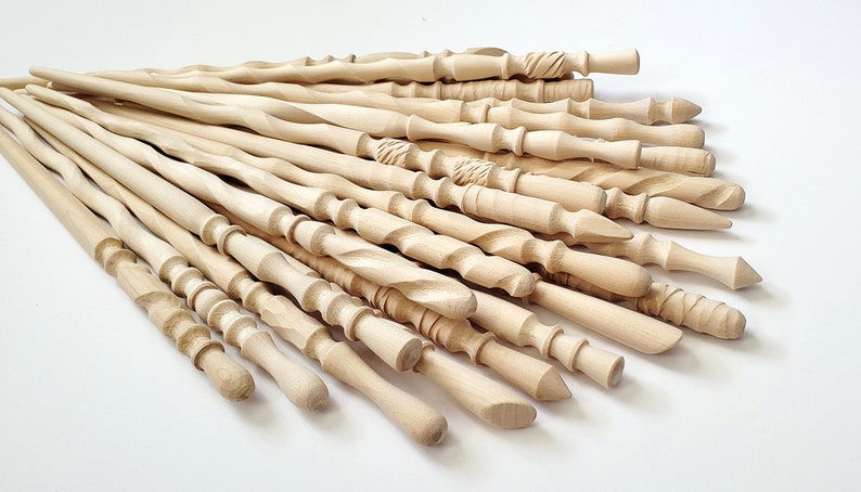 May include: A collection of 20 wooden wands, each with a unique design and shape. The wands are made of light-colored wood and have a smooth, polished finish.