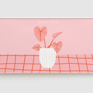 Könnte beinhalten: Ein gerahmter Druck mit rosa Hintergrund und einem weißen Topf mit einer Pflanze mit roten Blättern. Der Text "PERFECT TO ME" ist in weiß auf dem rosa Hintergrund geschrieben.