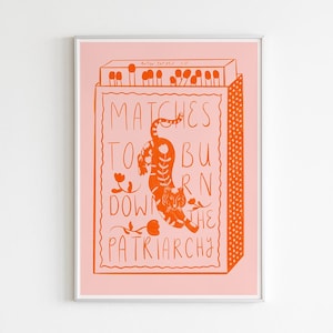 Könnte beinhalten: Gerahmter Kunstdruck mit rosa Hintergrund und orangefarbener Illustration. Die Illustration zeigt eine Streichholzschachtel mit Streichhölzern und einem Tiger, mit den Worten "Matches to Burn Down the Patriarchy."