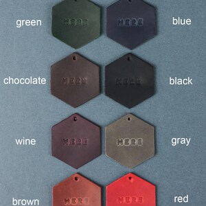 May include: Nine leather swatches in hexagon shapes, each with the word "MERE" embossed in the center. The swatches are arranged in three rows of three, with the colors green, blue, black, wine, gray, red, chocolate, and brown.