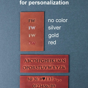 May include: Image of leather samples for personalization. The image displays letter, number, and symbol options, with colour choices: no colour, silver, gold, and red. Text at the top reads "Choose letters and colour for personalization".