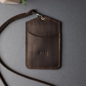 May include: Brown leather ID card holder with a lanyard and the initials "PAH" embossed on the front.