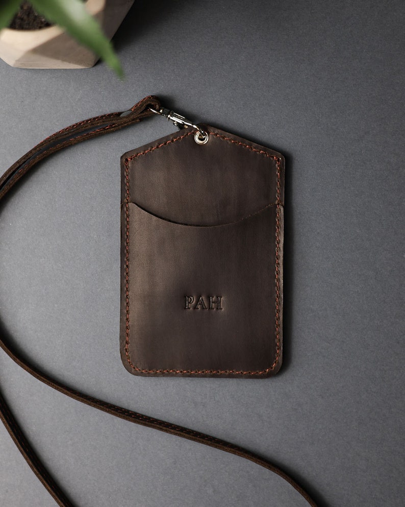 May include: Brown leather ID card holder with a lanyard and the initials "PAH" embossed on the front.