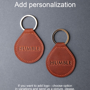 May include: Two brown leather keychains with silver key rings. The keychains are shaped like teardrops and have the word "HUMBLE" embossed on them.