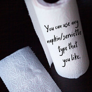 May include: A white paper towel roll with the text "You can use any napkin/serviette type that you like." written on it.