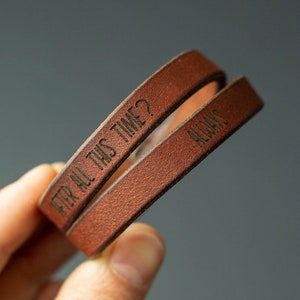 Può includere: Due braccialetti in pelle marrone con il testo "After all this time?" e "Always" inciso su di essi.