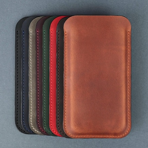 May include: A set of eight leather phone cases in various colors, including navy blue, gray, burgundy, green, red, black, and brown. The cases are lined up in a row, with the brown case at the front.