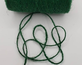 May include: A roll of green twine, with a length of twine unraveled and lying on a white surface.