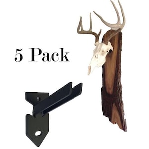 May include: Five pack of black metal wall mounts for displaying deer antlers. The mounts are shaped like an arrow pointing up. The image also shows a deer skull mounted on a wooden plaque.