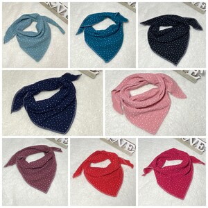 Könnte beinhalten: Set mit zehn Baumwoll-Bandana-Lätzchen in verschiedenen Farben mit weißen Punkten. Die Lätzchen sind dreieckig und haben einen genähten Rand.