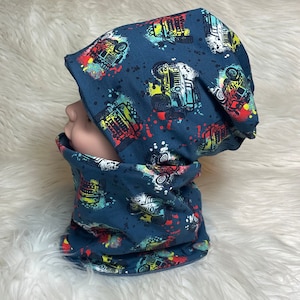 May include: A blue beanie and neck warmer set with a colorful print of off-road vehicles and paint splatters.