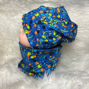 May include: A blue and black beanie with a colorful paint splatter pattern. The beanie is made of soft, comfortable fabric and is perfect for keeping warm in the winter.