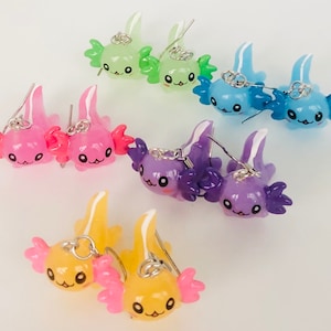 May include: A set of 10 colourful axolotl earrings. The earrings are made of polymer clay and feature a cute, cartoon-like axolotl design. The earrings are available in a variety of colours, including pink, blue, purple, green, and yellow.