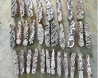 Op de afbeelding: Een set van 30 houten stempels met ingewikkelde bloem- en paisleymotieven. De stempels zijn gesneden met witte motieven op een natuurlijke houten achtergrond.