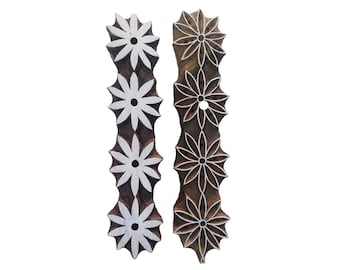May include: Two wooden printing blocks with floral designs. Each block has four flower shapes in a row. The flowers are white and have a small circle in the center. The blocks are brown and have a natural wood grain.