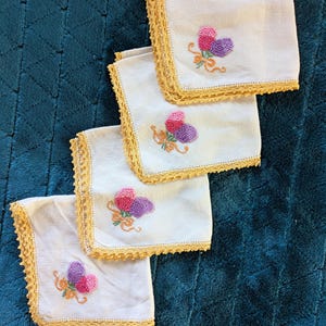 May include: A white ceramic mug with a black handle and the text "But First, Coffee" in a bold, black font. The mug is set against a blurred background, suggesting a cozy setting.