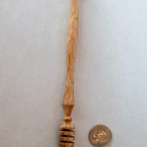 Pu&ograve; includere: Un mestolo di miele in legno con un manico lungo e sottile e un design a spirale sul fondo. Il mestolo &egrave; circa delle dimensioni di una moneta da 20 centesimi di euro.