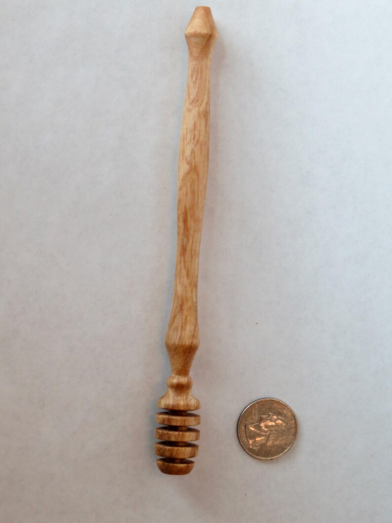 Pu&ograve; includere: Un mestolo di miele in legno con un manico lungo e sottile e un design a spirale sul fondo. Il mestolo &egrave; circa delle dimensioni di una moneta da 20 centesimi di euro.