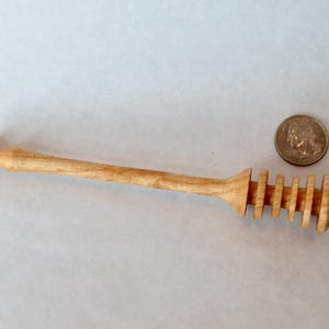 Pu&ograve; includere: Un mestolo per miele in legno con finitura naturale e un design a spirale all'estremit&agrave;. Il mestolo &egrave; lungo circa 18 cm.