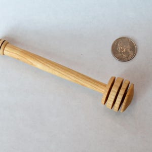 Pu&ograve; includere: Un mestolo di legno per il miele con un manico lungo e un'estremit&agrave; arrotondata e scanalata. Il mestolo &egrave; fatto di legno chiaro ed &egrave; circa delle dimensioni di una moneta da 25 centesimi di euro.