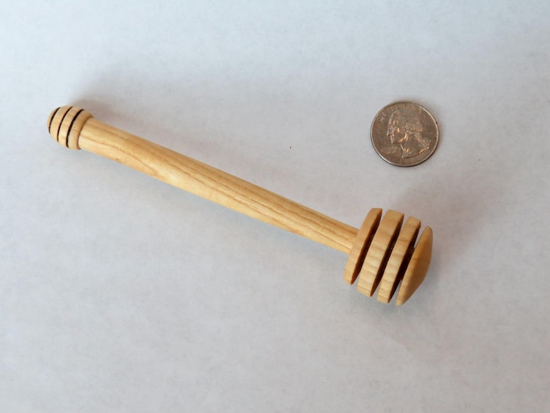 Pu&ograve; includere: Un mestolo di legno per il miele con un manico lungo e un'estremit&agrave; arrotondata e scanalata. Il mestolo &egrave; fatto di legno chiaro ed &egrave; circa delle dimensioni di una moneta da 25 centesimi di euro.