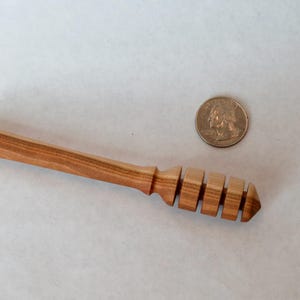 Pu&ograve; includere: Un mestolo per miele in legno con finitura in legno naturale e un design a nido d'ape. Il mestolo &egrave; lungo circa 15 cm.