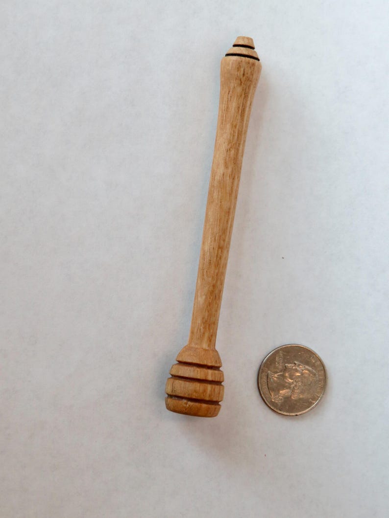 Pu&ograve; includere: Un mestolo di legno per il miele con un'estremit&agrave; arrotondata e scanalata e un manico lungo e sottile. Il mestolo &egrave; circa delle dimensioni di una moneta da 20 centesimi di euro.