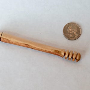 Pu&ograve; includere: Un mestolo di legno per il miele con un manico intagliato e un'estremit&agrave; a forma di favo. Il mestolo &egrave; circa delle dimensioni di una moneta da un euro.