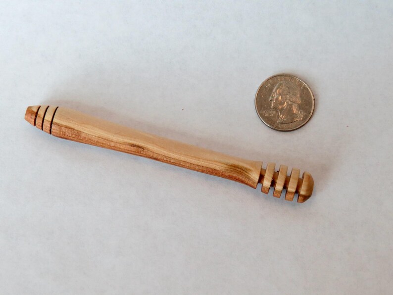 Pu&ograve; includere: Un mestolo di legno per il miele con un manico intagliato e un'estremit&agrave; a forma di favo. Il mestolo &egrave; circa delle dimensioni di una moneta da un euro.