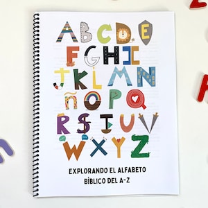 Könnte beinhalten: Ein spiralgebundenes Buch mit einem weißen Einband, auf dem ein farbenfrohes Alphabet mit Illustrationen abgebildet ist. Der Titel des Buches lautet "EXPLORANDO EL ALFABETO BÍBLICO DEL A-Z".