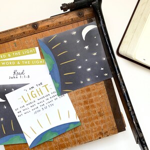 May include: A set of printable cards with a blue and green earth illustration, a crescent moon, and stars. The cards feature the text "The Word & The Light", "Read John 1:1-5", "I am the Light of the world. Whoever follows me will not walk in darkness, but will have the light of life. John 8:12 ESV".