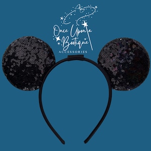 May include: Black sequin mouse ears headband with the text "Once Upon a Boutique Accessories" in white script. The ears are round and covered in black sequins. The headband is black.