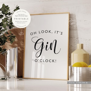 May include: A rectangular wall art print in a thin wooden frame featuring the black text OH LOOK, IT'S GIN O'CLOCK! on a white background. The design includes a circular badge in the top left corner with text and a download icon, plus a logo in the top right.