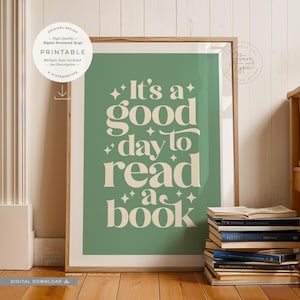 Może przedstawiać: Oprawiony wydruk z napisem "It's a good day to read a book" w kremowej czcionce na zielonym tle. Wydruk jest w drewnianej ramie i jest wyświetlany obok stosu książek.