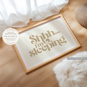 May include: A framed print with the text "Shhh... I'm sleeping" in a stylish font. The print has a light beige background and a wooden frame. The image is a digital download.