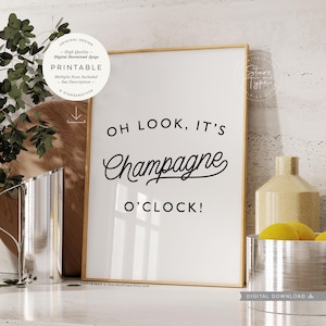 Könnte beinhalten: Ein druckbarer Wandkunstdruck mit goldenem Rahmen und weißem Hintergrund. Der Text auf dem Druck lautet "Oh look, it's Champagne o'clock!" in schwarzer Kursivschrift.